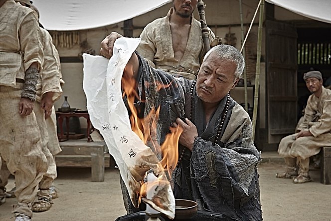 뭔가 적혀있는 종이를 태우고 있는 '땡추'